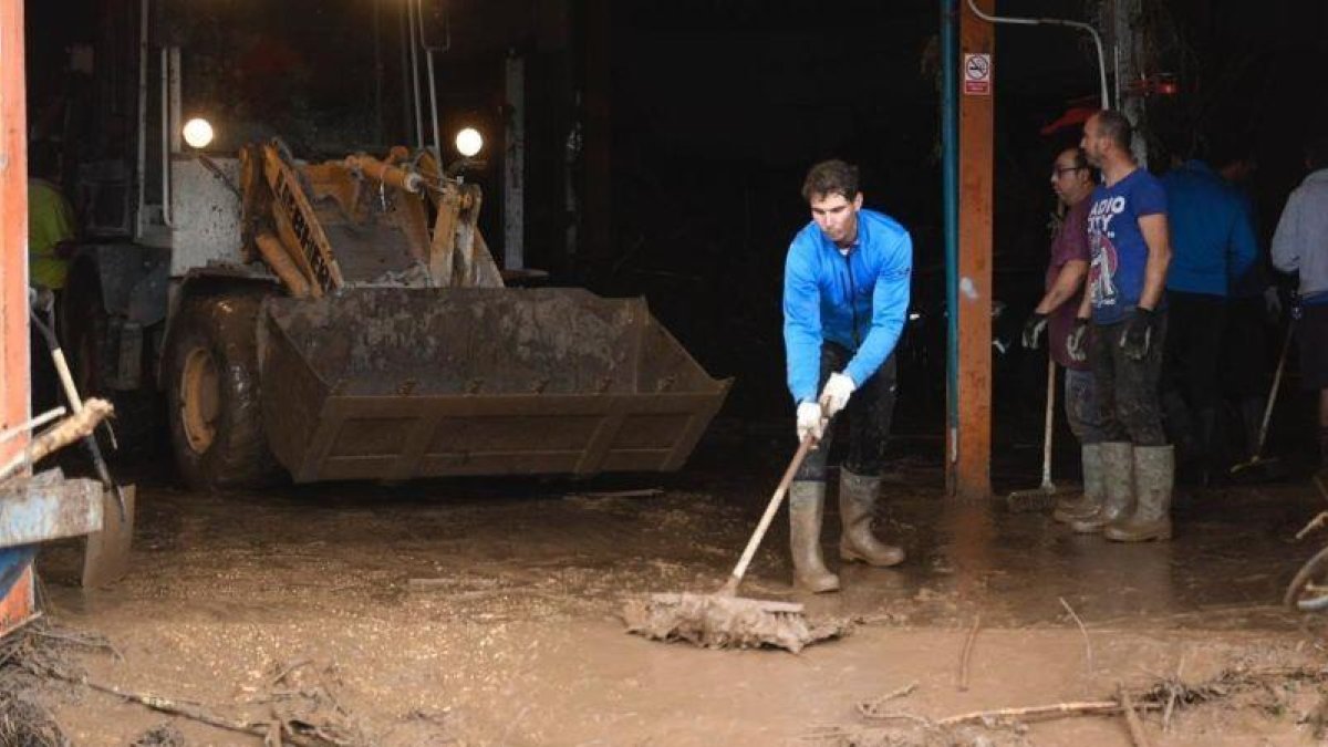 El tenista Rafa Nadal participa este miércoles en las tareas de limpieza en un taller mecánico de Sant Llorenç, tras las lluvias.