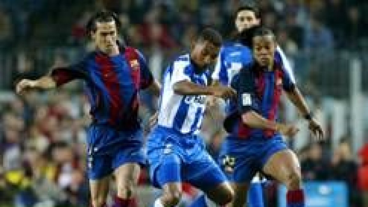 Luis García y Ronaldinho pelean la posesión de un balón que controla Mauro Silva
