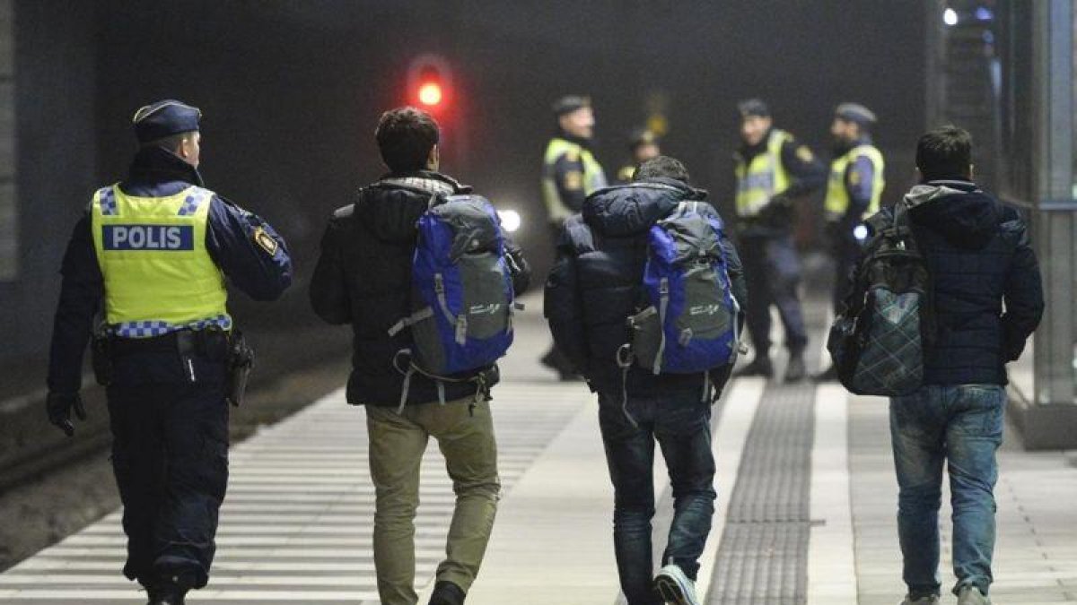 Policías suecos acompañan a dos refugiados en la estación de tren de Hyllie, en Malmo.
