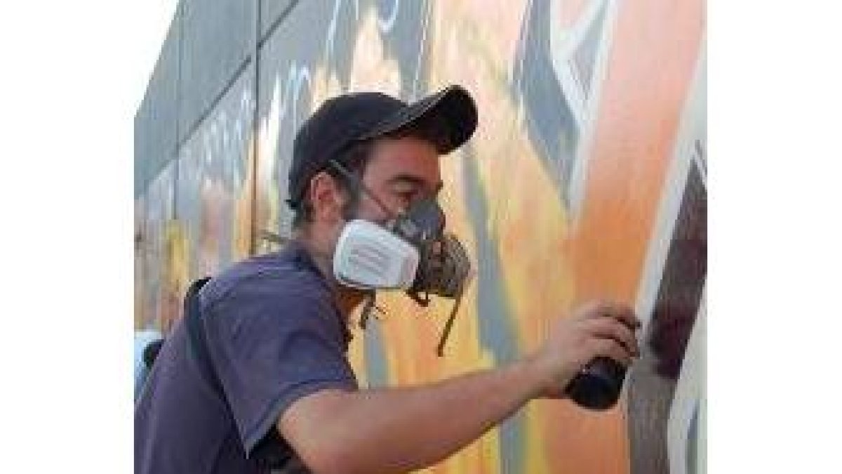 Uno de los graffiteros acabando su dibujo del muro del campo de fútbol de San Andrés