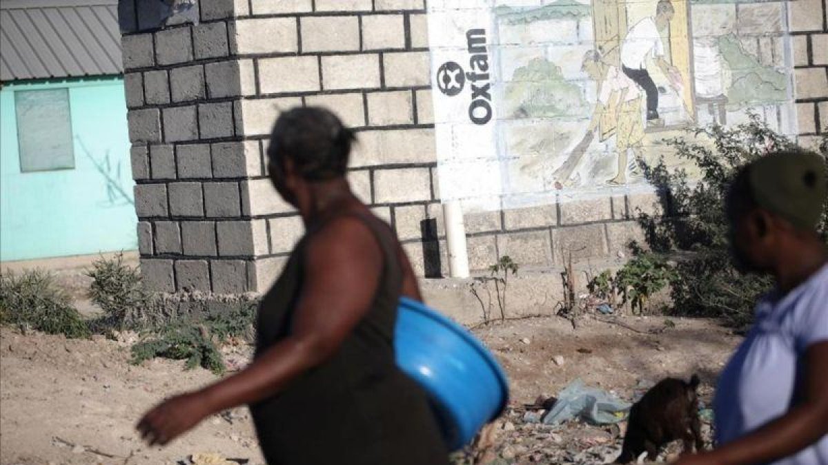 Dos mujeres pasan ante un mural de Oxfam en Puerto Príncipe, Haití.