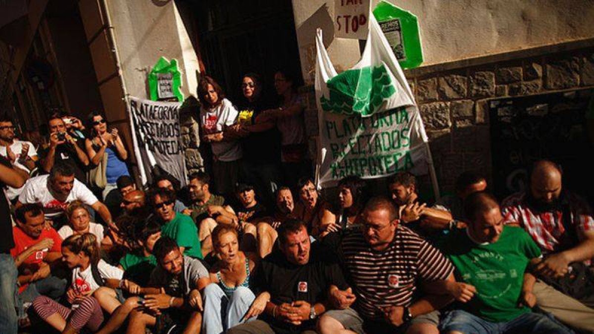 Miembros de movimientos Stop Desahucios y PAH bloquean la puerta de la vivienda de Rebeca Heredia, en Málaga, para evitar su desalojo, aplazado hasta octubre.
