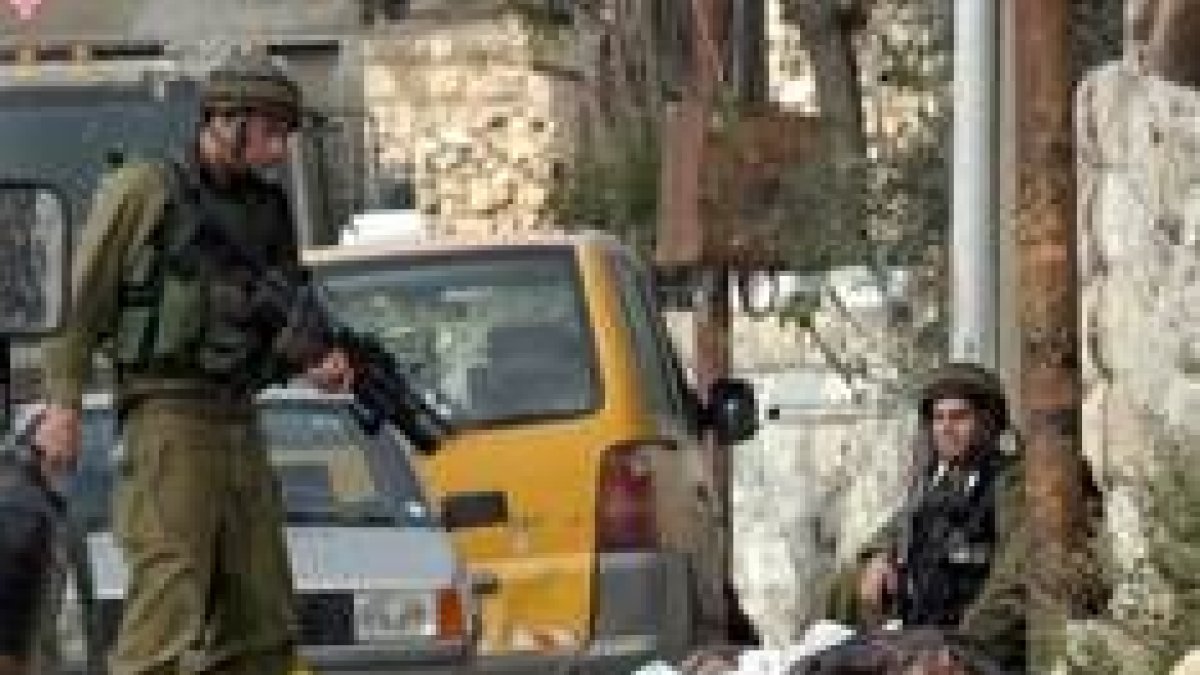 Dos soldados israelíes contemplan el cadáver de uno de los palestinos