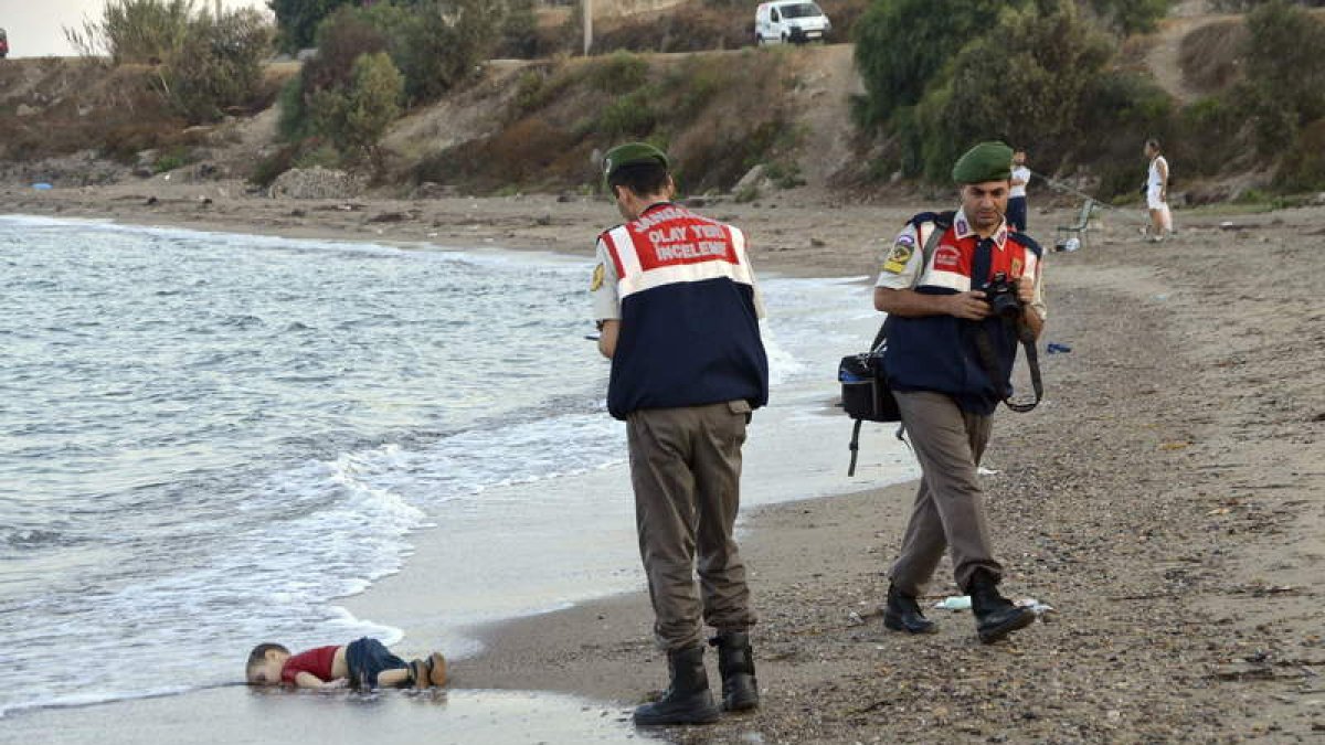 Dos policías turcos trabajan junto al cuerpo sin vida de un niño refugiado ahogado en Turquía.