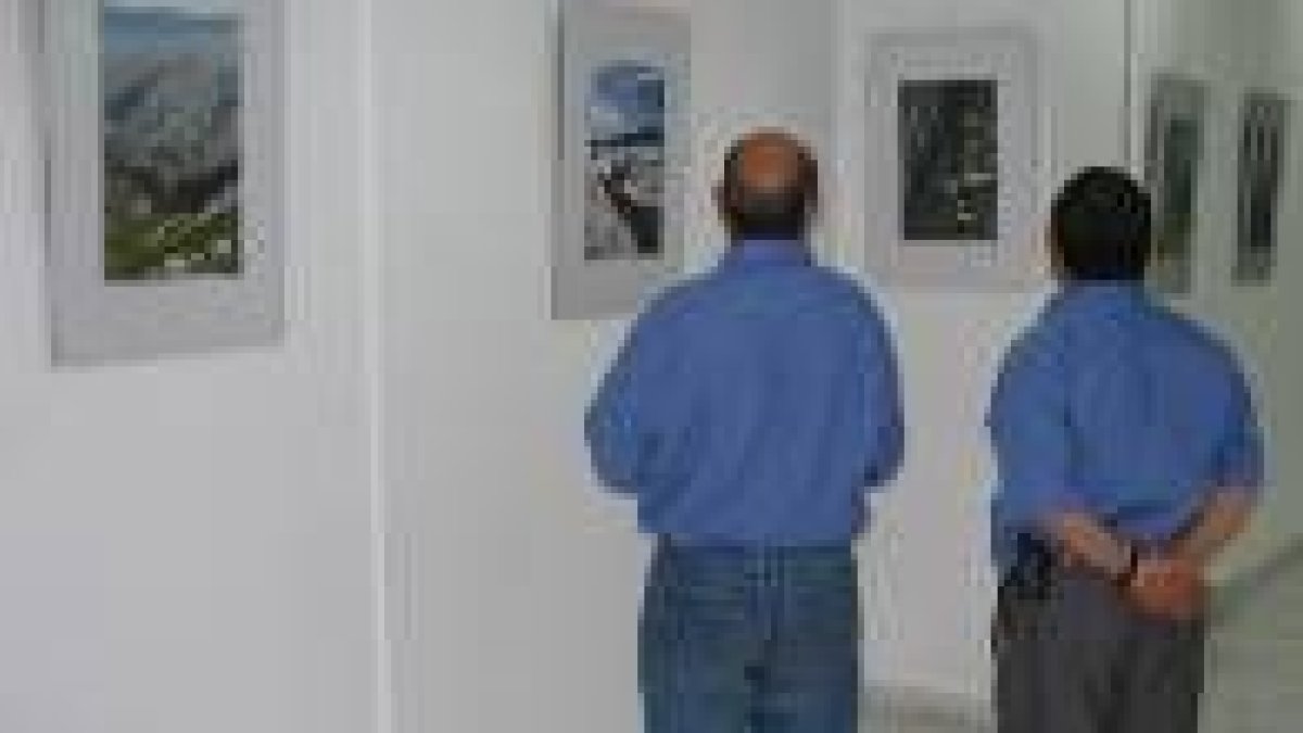 Dos hombres contemplan la exposición fotográfica de la biblioteca