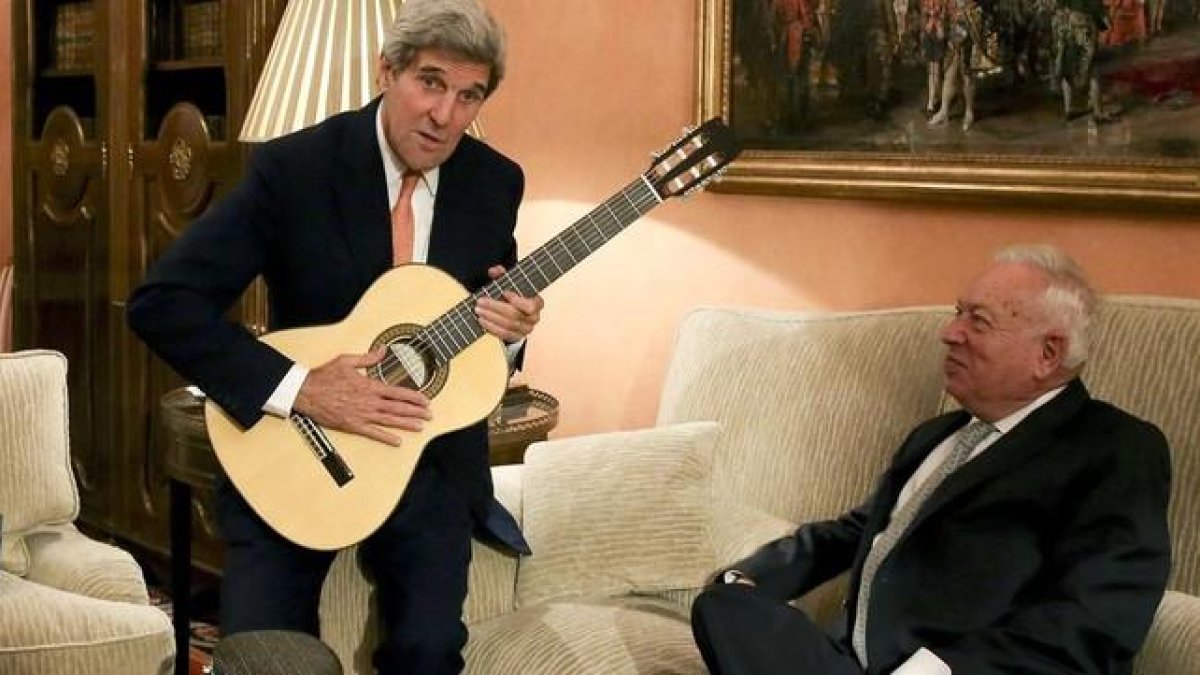 Kerry con la guitarra española que le ha regalado Margallo, sentado en el sofá, esta tarde en el Palacio de Viana, en Madrid.