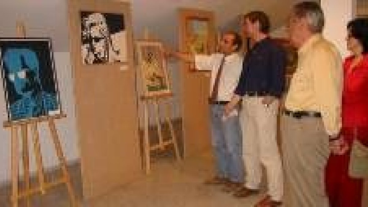 El concejal de Cultura señala al artista una de sus obras en presencia de algunos visitantes