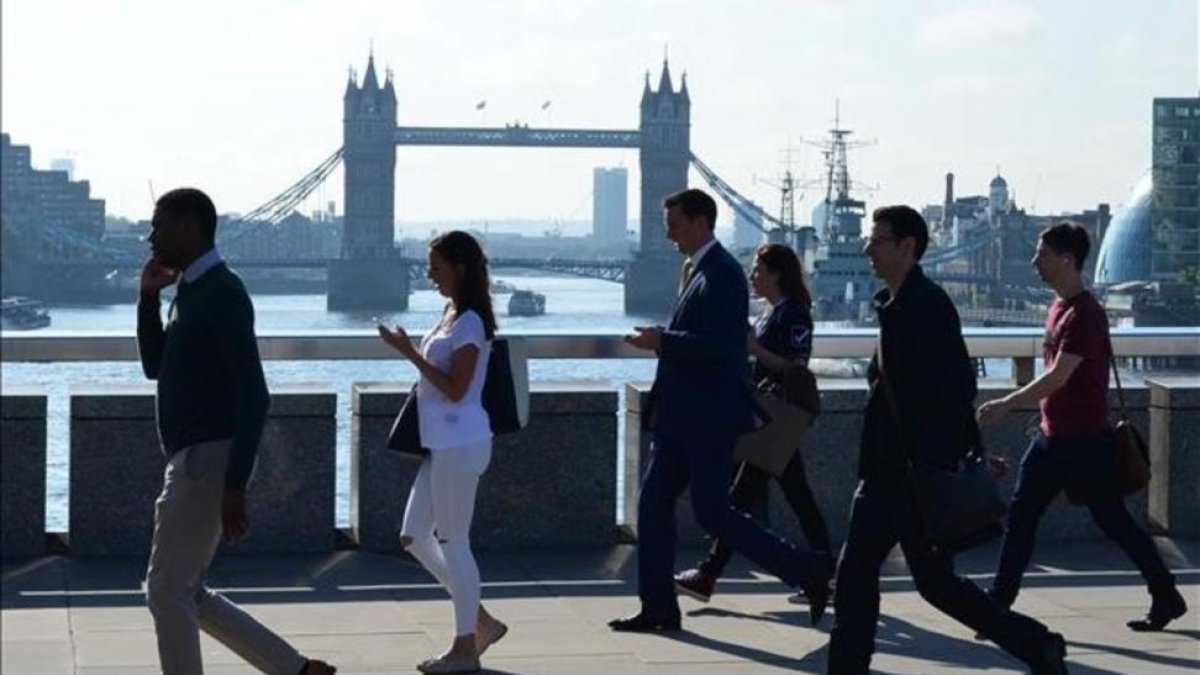 Varios transeúntes se dirigen a la City cruzando el puente de Londres, frente al puente de la Torre de Londres, el 24 de junio.