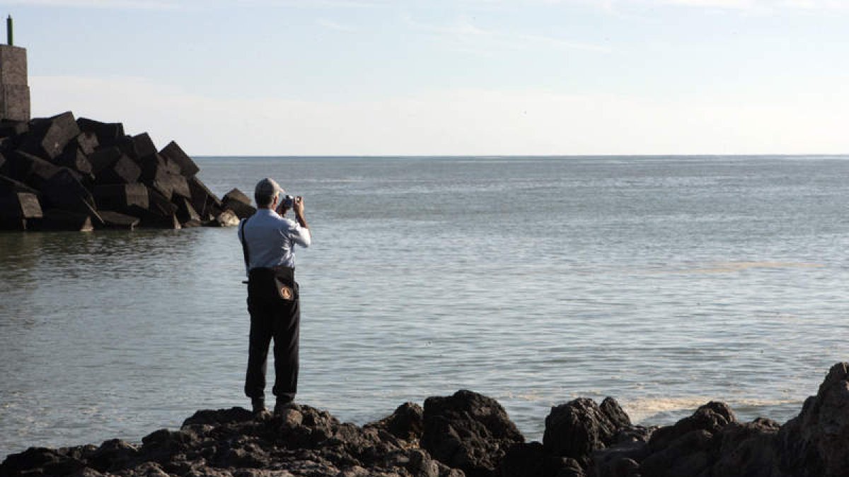 Un hombre observa la mancha desde el puerto de La Restinga.