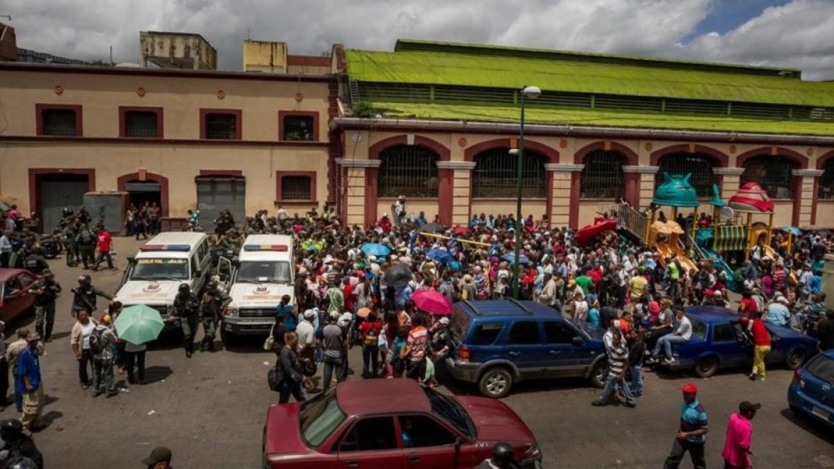 Un grupo de personas hace fila para poder comprar alimentos el martes en Caracas.