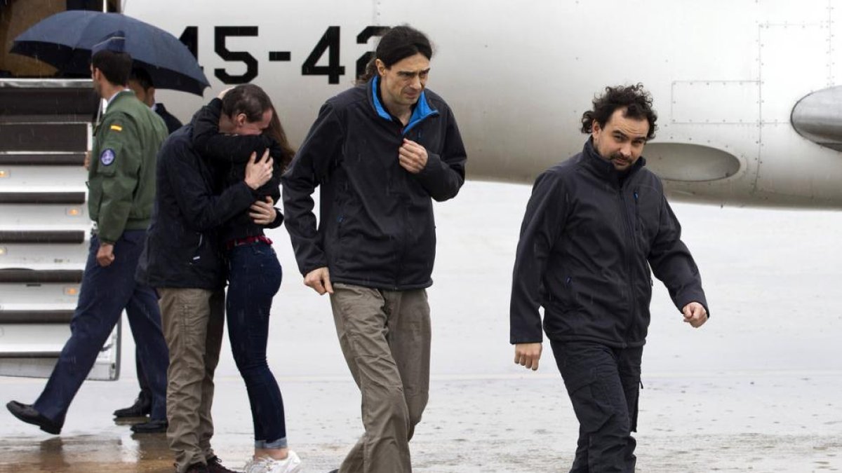 Los periodistas españoles Ángel Sastre (derecha), José Manuel López (centro) y Antonio Pampliega (abrazando a un familiar), a su llegada esta mañana a la Base Aérea de Torrejón de Ardoz, en Madrid.