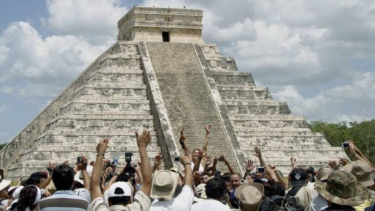 Ciudadanos y turistas en una celebración ante la pirámide central de las ruinas de Chichen Itza, en México.