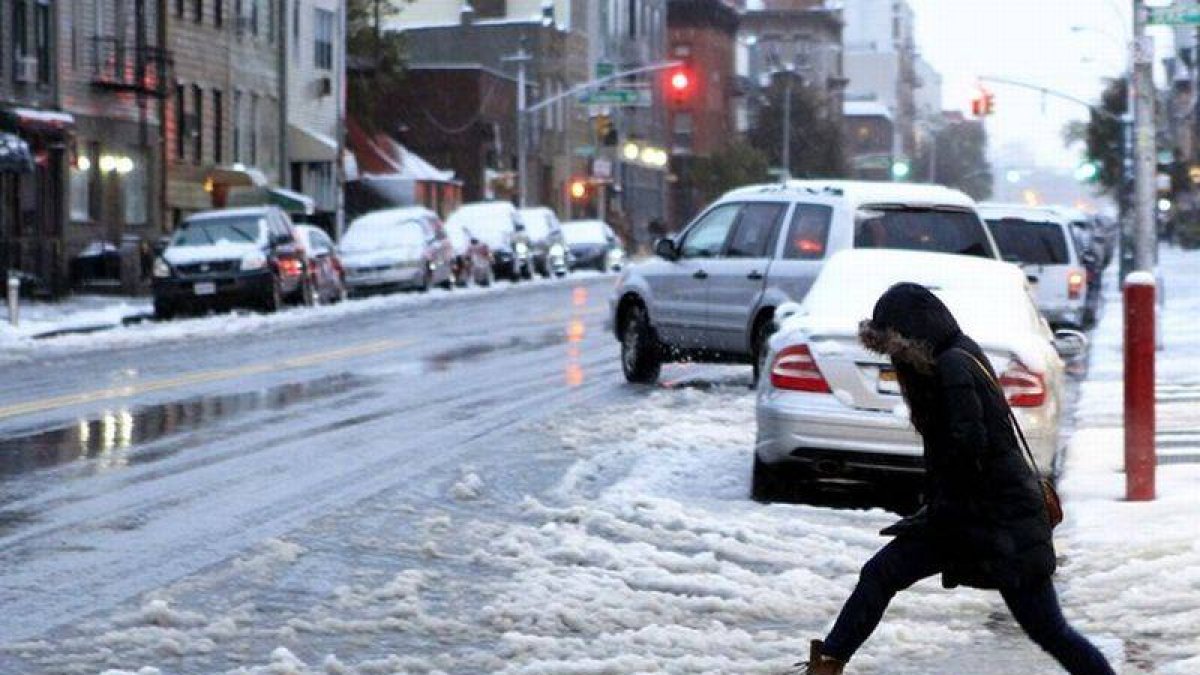 Una mujer cruza una calle nevada en Nueva York.