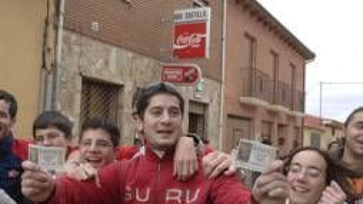 Varios vecinos de Villardefrades celebran a las puertas del bar autosevicio el Gordo de la lotería