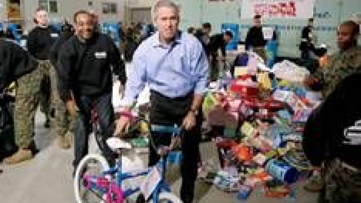 Bush lleva una bicicleta durante su visita a un centro de colecta de juguetes para niños necesitados