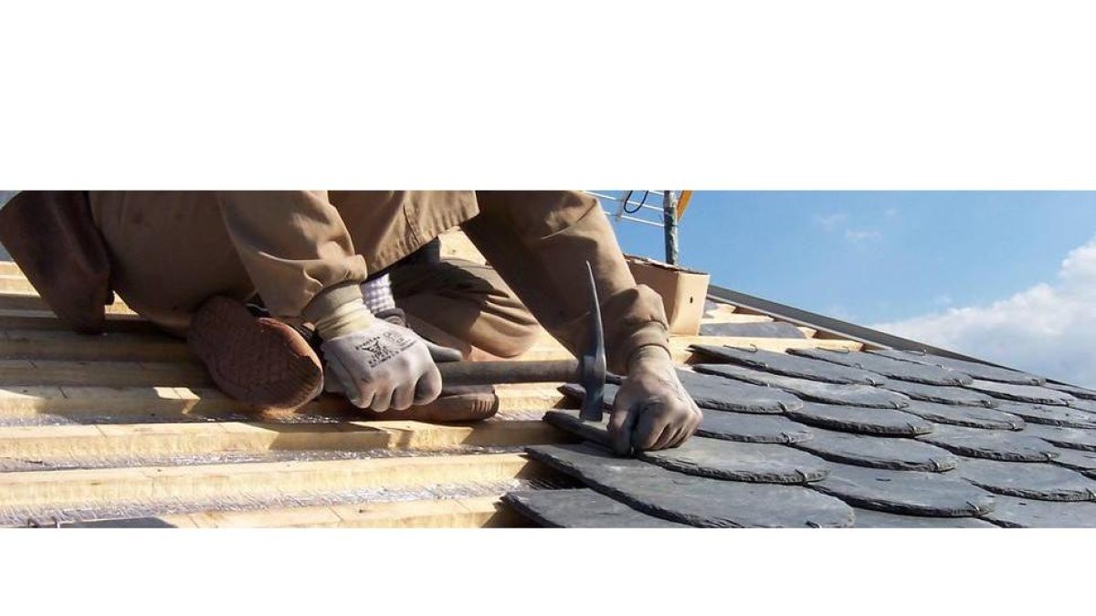 Un trabajador coloca pizarra en un tejado