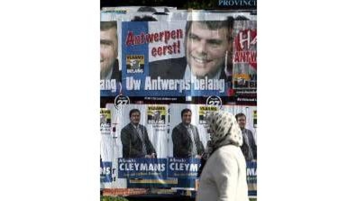 Una mujer pasa en Berchem ante los carteles electorales de Interés Flamenco