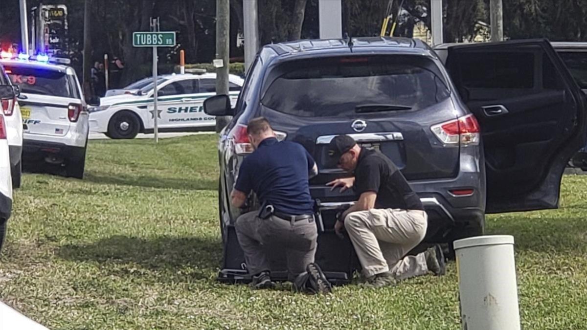 Agentes de policía se protegen tras su vehículo durante el tiroteo en el banco de Florida, este miércoles.