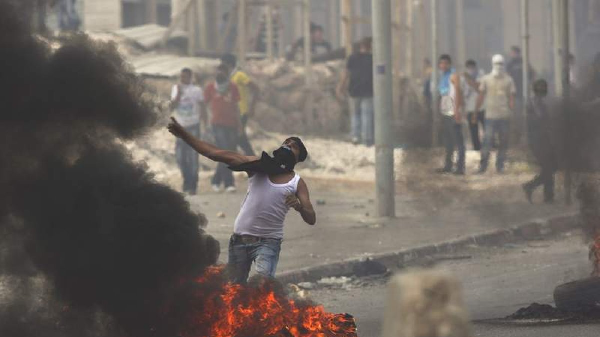 Un joven palestino lanza piedras a los soldados israelíes en el puesto fronterizo de Kalandia.