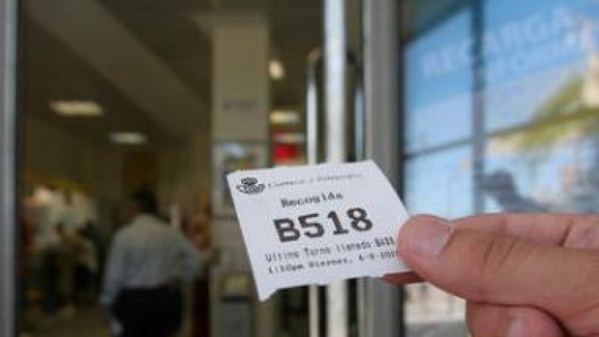 Un usuario muestra el número 518 de la cola de espera, ayer a las doce y media en Correos.