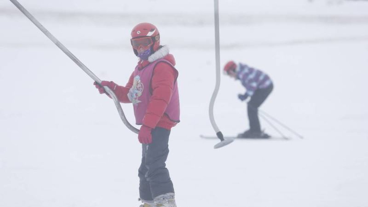 Un niño coge un arrastre en el curso de esquí que se celebra en San Isidro
