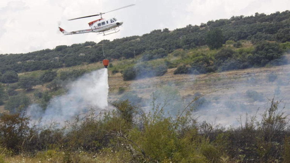 Un helicóptero arroja agua sobre el foco, posiblemente intencionado, que se inició ayer en la Ercina. CAMPOS