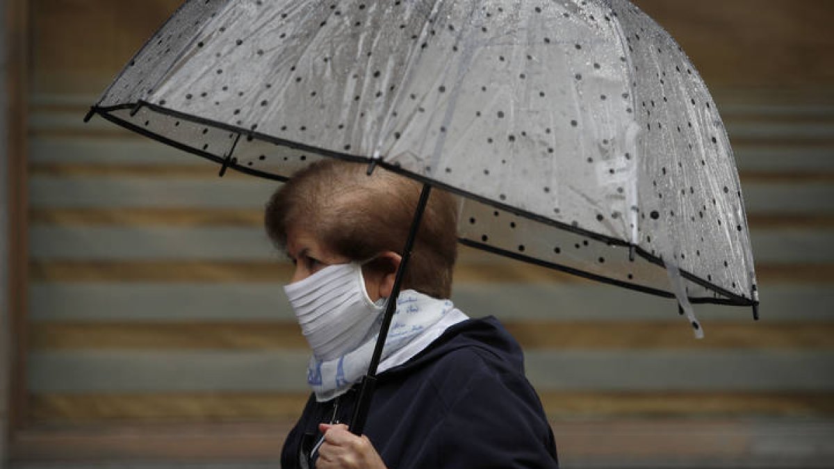 Una mujer, bajo la lluvia leonesa con su mascarilla casera. JESÚS F. SALVADORES