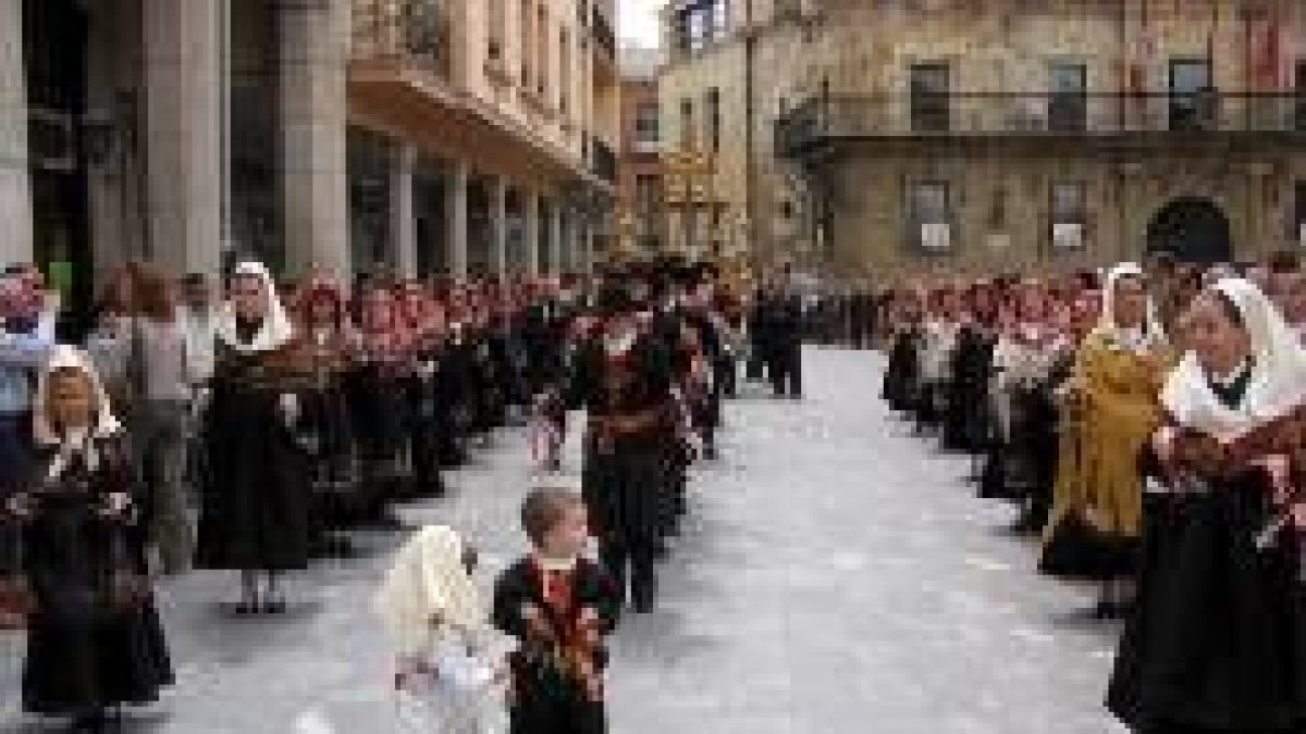 Fieles vestidos de maragatos desfilan por Astorga, acompañando a la Cruz Dorada