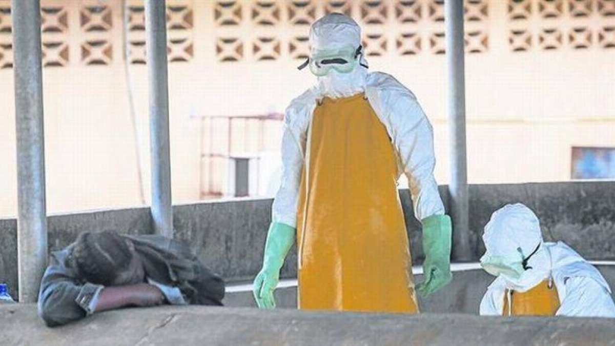 Dos sanitarios se dirigen a recoger el cadáver de una fallecida por ébola en Monrovia.