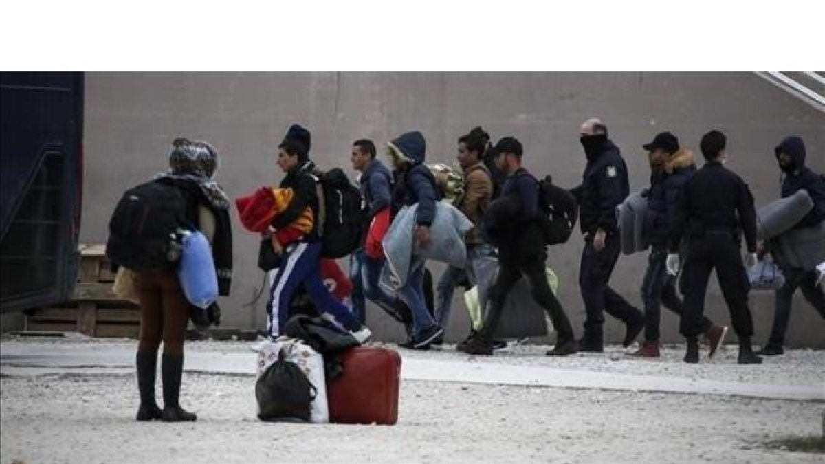 La policía griega escolta a inmigrantes en el exterior de un estadio en el sur de Atenas.