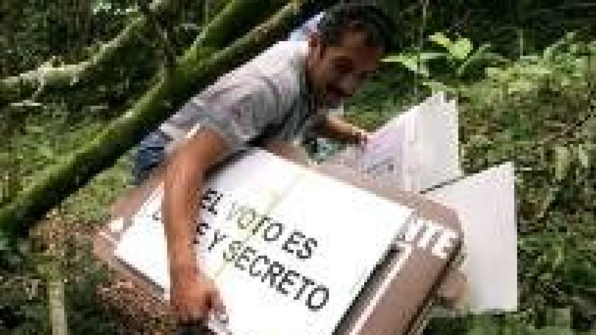 Un agentes electoral lleva por la selva las urnas y pancartas electorales