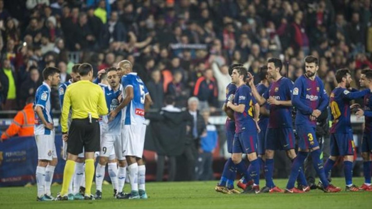PROTESTA FINAL Los jugadores del Espanyol protestan al árbitro mientras los futbolistas del Barça celebran la clasificación para las semifinales de Copa, ayer, en el Camp Nou.
