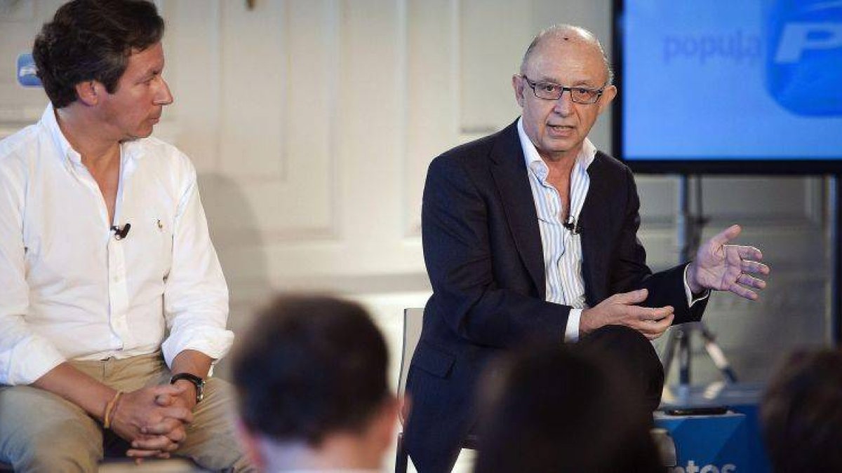 El ministro de Hacienda, Cristóbal Montoro (d), y el vicesecretario general de Organización del PP, Carlos Floriano, durante su intervención en la clausura del Debate organizado por el partido sobre los Presupuestos Generales del Estado.