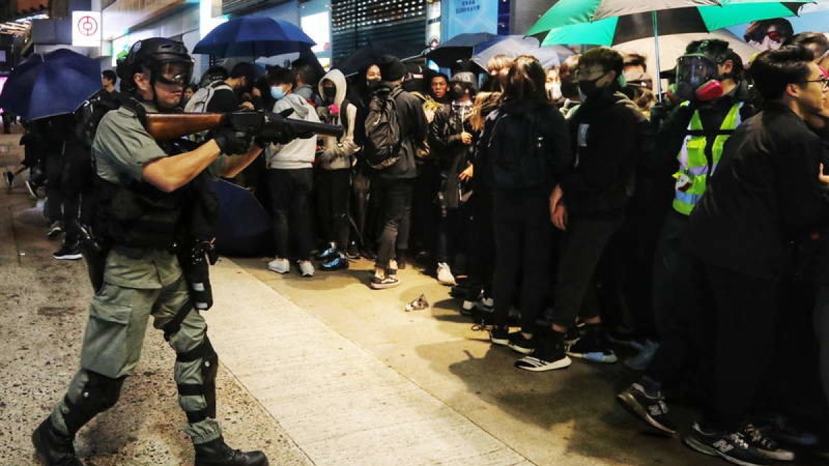 Un policía de Hong Kong intenta tener bajo control a un grupo de manifestantes.