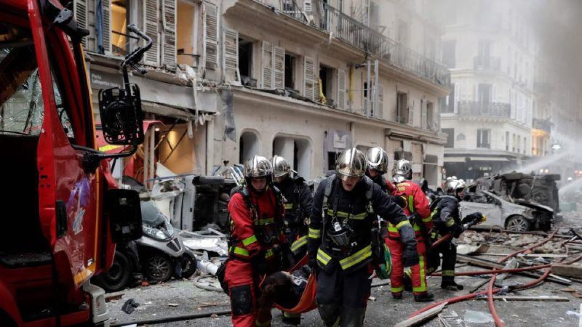 Los bomberos trasladan a una herida en la explosión en una panadería en París, este sábado.