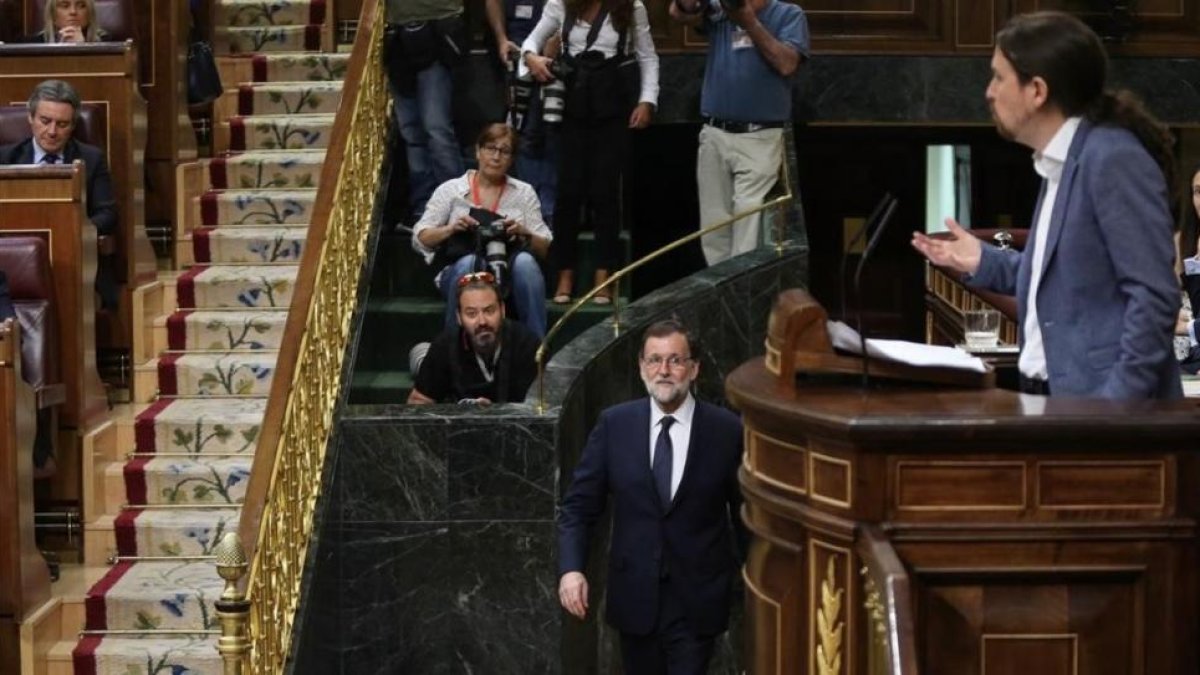 Mariano Rajoy vuelve a su escaño tras unos minutos fuera del hemiciclo mientras Pablo Iglesias habla en la tribuna.