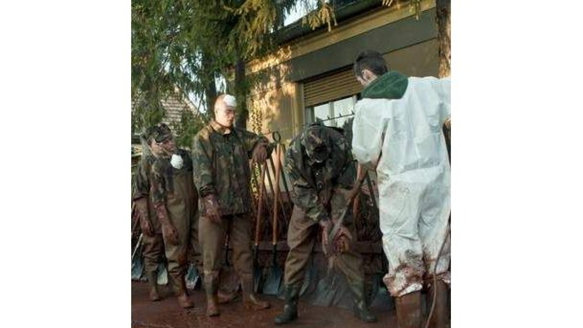 Soldados hacen fila para ser limpiados tras recoger lodo.