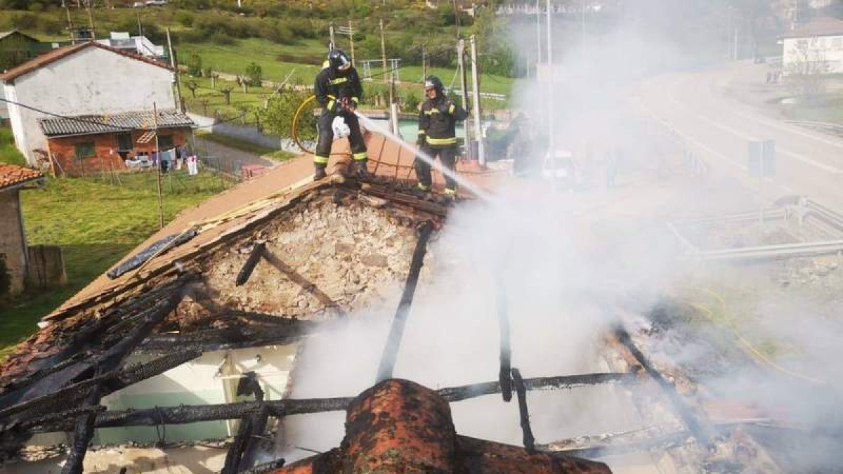 Dos bomberos actúan en el tejado del edificio siniestrado. BOMBEROS DE LEÓN