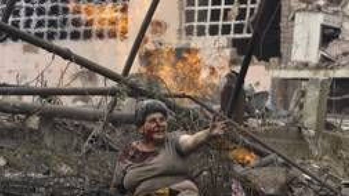 Una mujer herida entre los escombros de un edificio bombardeado
