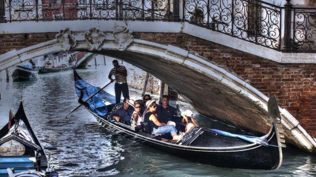 Unos turistas pasean en góndola por Venecia.