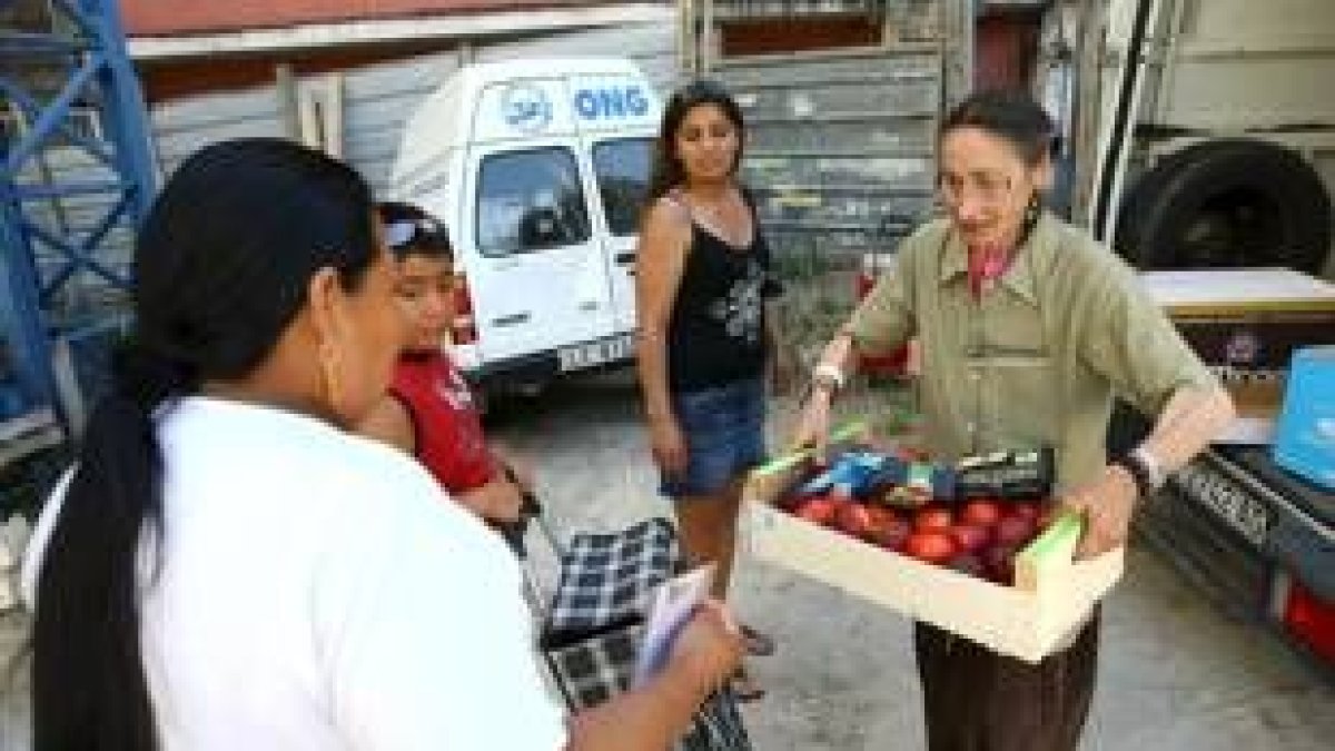Una voluntaria del Banco de Alimentos del Sil entrega a una familia de inmigrantes una caja de fruta