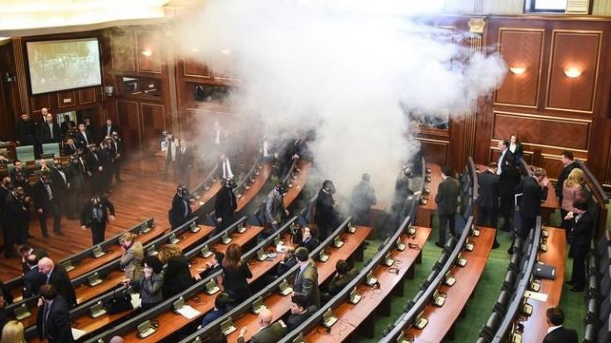 Diputados kosovares evacúan la sala tras el lanzamiento del gas, en la primera sesión parlamentaria del año, en Pristina.