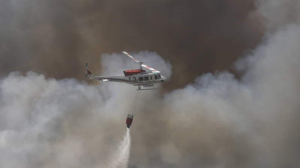 Un helicóptero descarga agua en la zona en llamas. MARCIANO PÉREZ