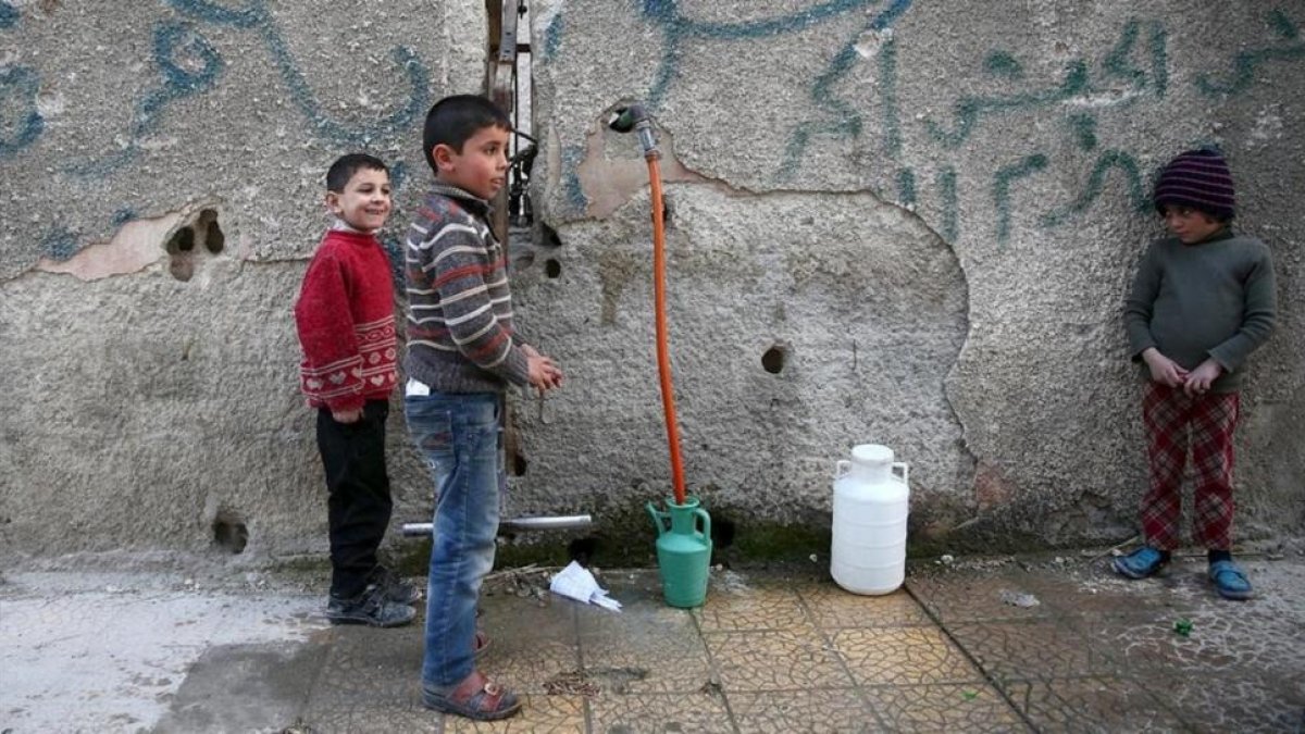 Varios niños hacen acopio de agua en la ciudad siria de Duma, cerca de Damasco.