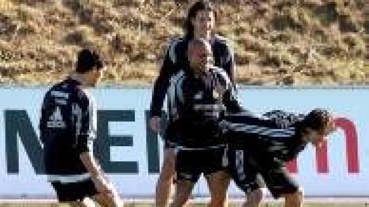 Roberto Carlos sonríe y sujeta a Morientes en presencia de otros compañeros durante un entrenamiento