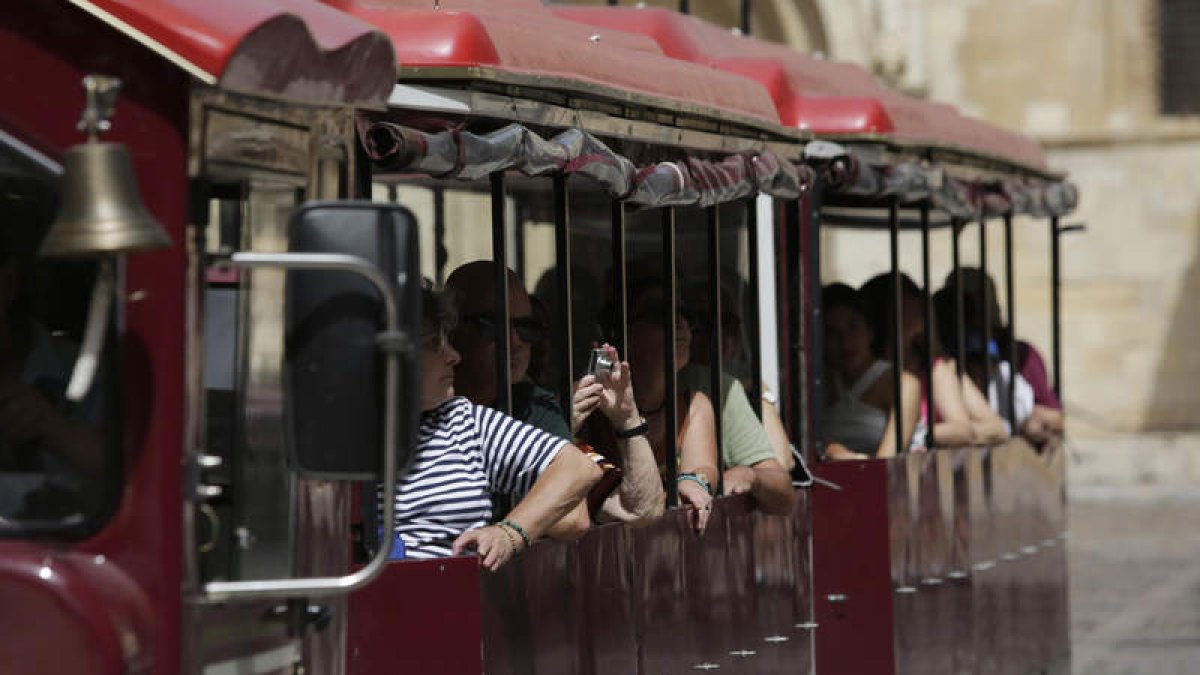 Turistas en el tren turístico de la ciudad, ayer tras pasar ante San Isidoro. FERNANDO OTERO.