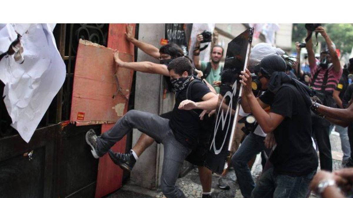Manifestantes intentan romper una puerta durante los enfrentamientos con la Policía Militarizada brasileña.