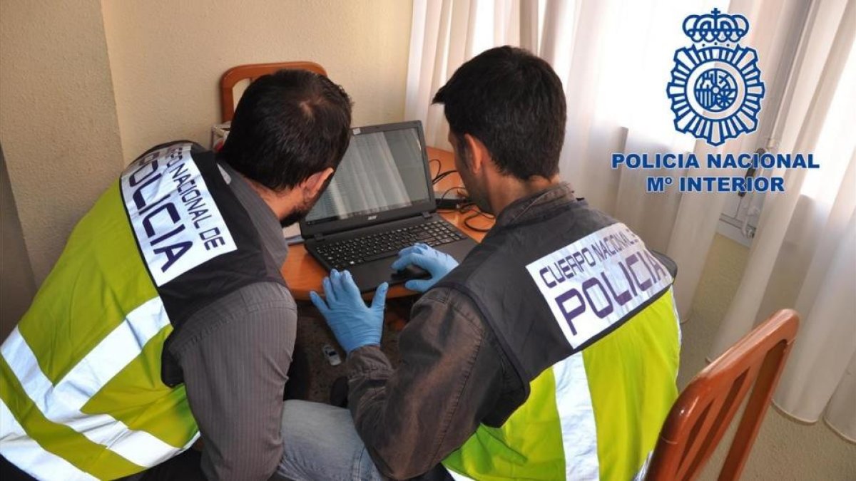 Dos agentes de la Policía Nacional inspeccionan un ordenador con material pornográfico.