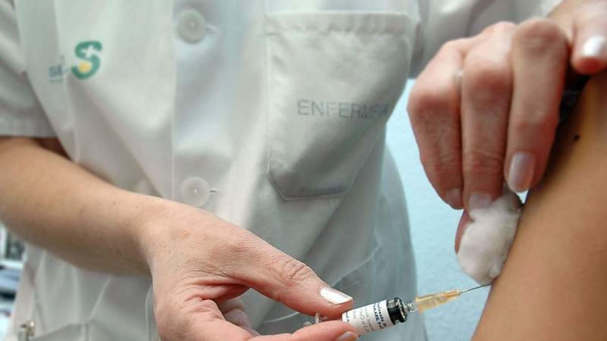Una sanitaria aplica una vacuna a un paciente.