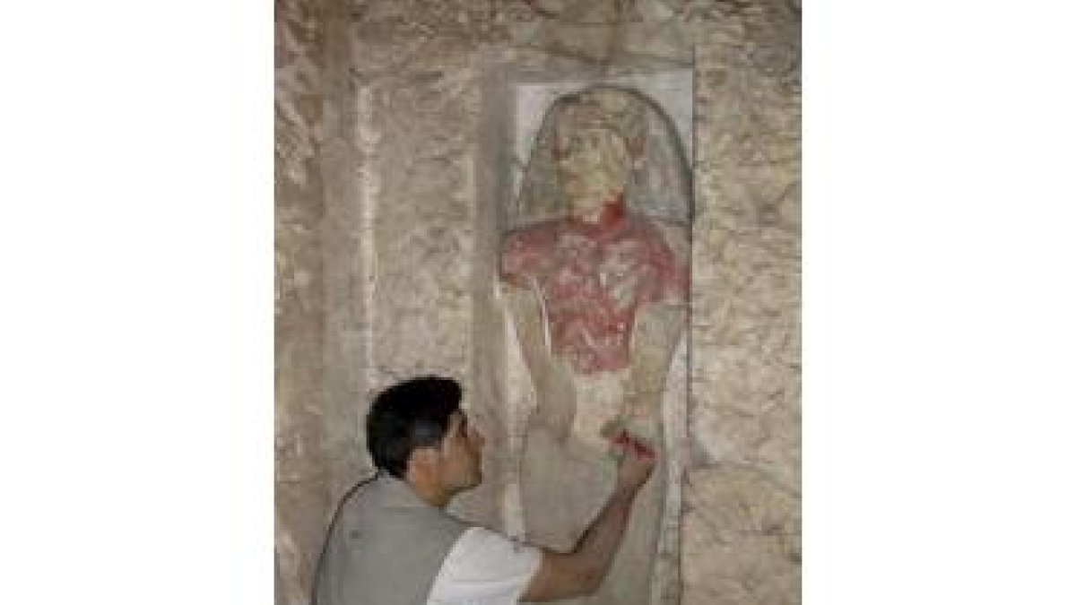 Un miembro del equipo limpia una de las imágenes de la tumba